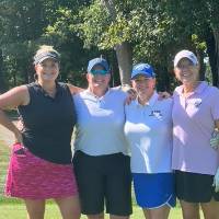 Four women playing golf.